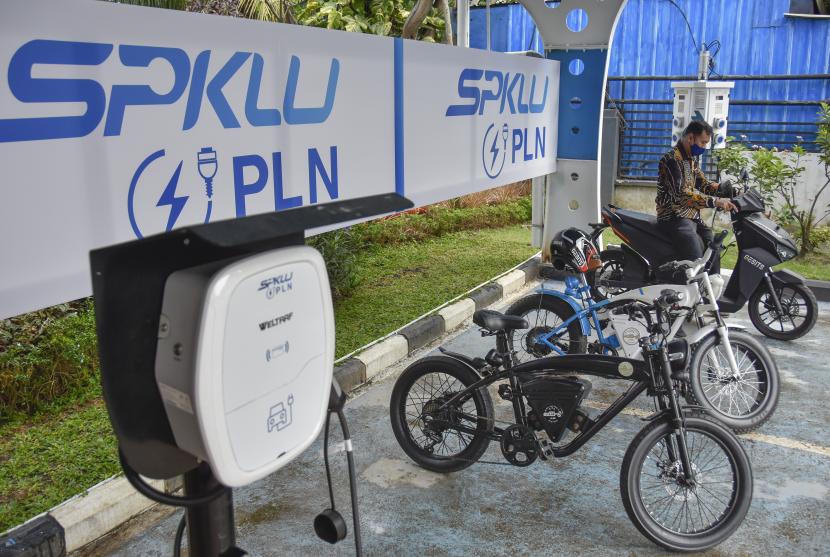 Seorang laki-laki mengisi daya sepeda motor listriknya di Stasiun Pengisian Kendaraan Listrik Umum (SPKLU) milik PT PLN (Persero). 