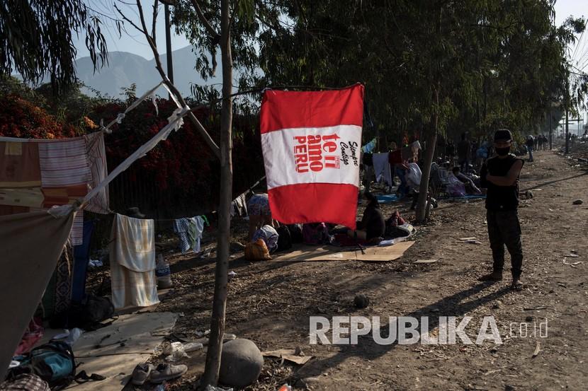 Seorang lelaki dari kelompok buruh dan pekerja informal yang biasanya mencari nafkah di ibukota Peru berdiri di sebelah bendera Peru bertuliskan bahasa Spanyol yang artinya Aku cinta Peru, ketika dia menunggu untuk pulang di Lima, Peru, Selasa (21/4).  Setelah tidak diizinkan meninggalkan ibukota karena peraturan karantina yang ketat saat pandemi virus Corona, buruh dan pekerja informal tersebut kini diperbolehkan untuk pulang. 