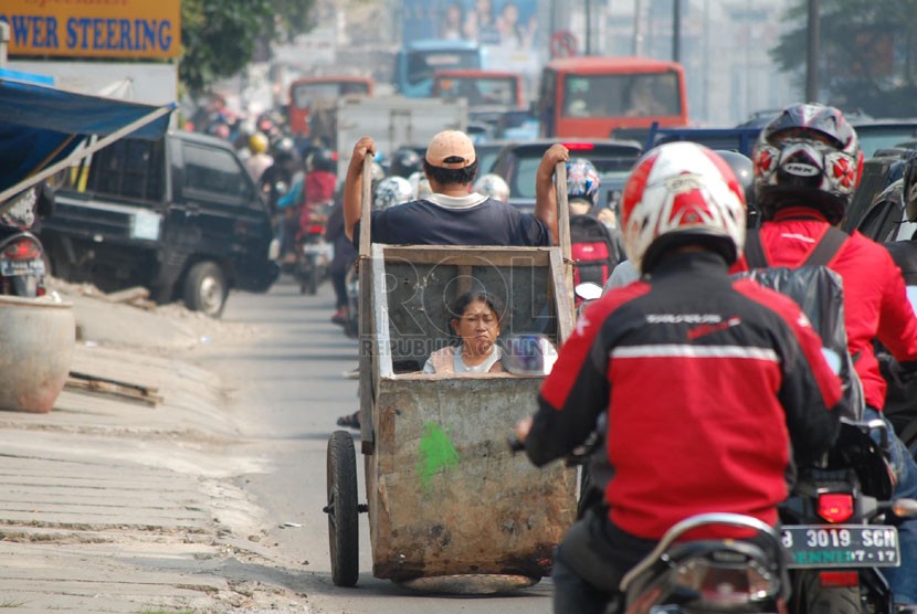 Seorang lelaki dari keluarga miskin mengangkut anak dan istrinya dengan gerobak di Jalan Panglima Polim, Jakarta Selatan. (foto: Raisan Al Farisi)