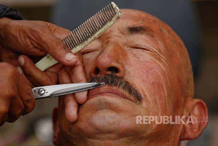 Seorang lelaki Uighur merapikan kumisnya di kedai cukur setempat di kota tua Khasgar, Daerah Otonomi Xinjiang Uighur, China. Peraturan pemerintah setempat melarang pria Uighur memanjangkan jenggot secara berlebihan dengan alasan ekstrimisme.