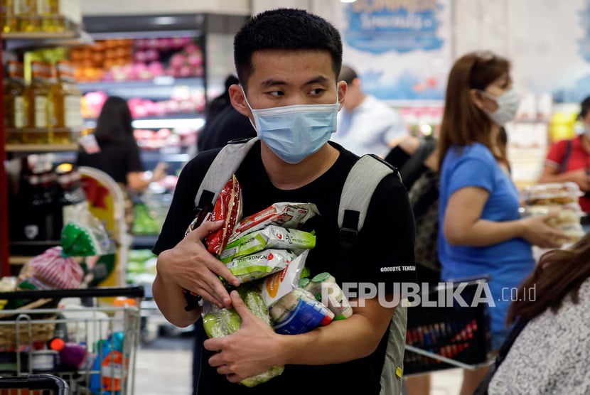 Warga mengenakan masker mengantre di sebuah toko kelontong di Taguig, kota metropolitan Manila, Filipina pada Jumat (13/3). Seorang WNI yang positif Covid-19 di Filipina masih jalani karantina mandiri.