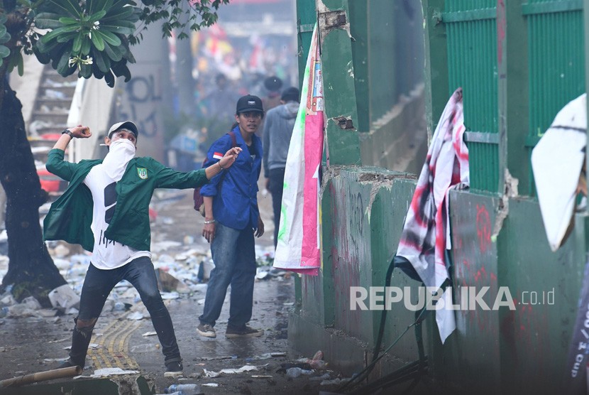 Seorang mahasiswa melemparkan batu ke arah polisi saat kericuhan dalam unjuk rasa di depan kompleks Parlemen di Jakarta, Selasa (24/9/2019). 