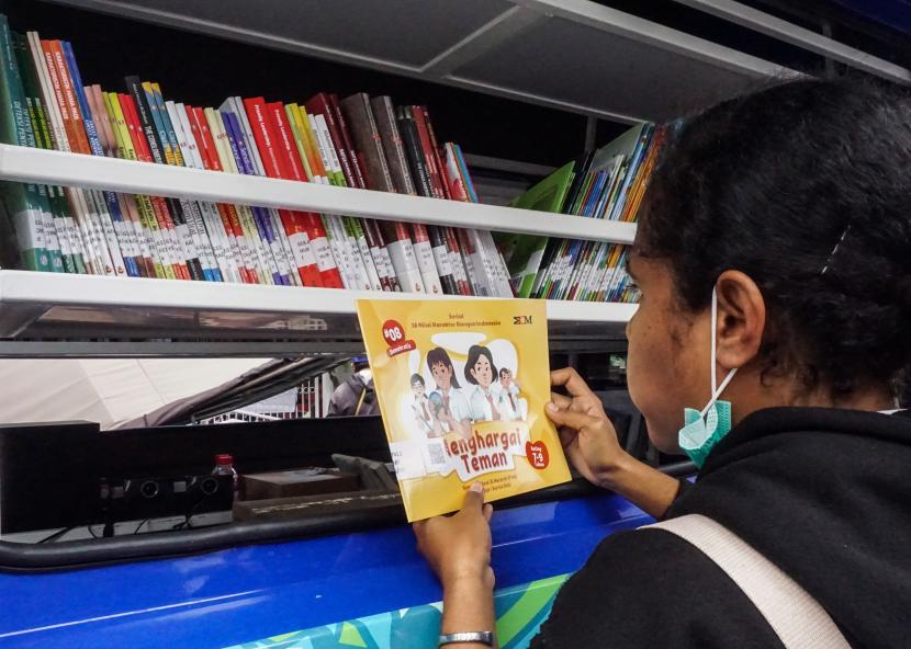 Seorang mahasiswa membaca di dekat mobil perpustakaan keliling di Jayapura, Papua beberapa waktu lalu. Perpustakaan Papua membutuhkan dana operasional keliling. 