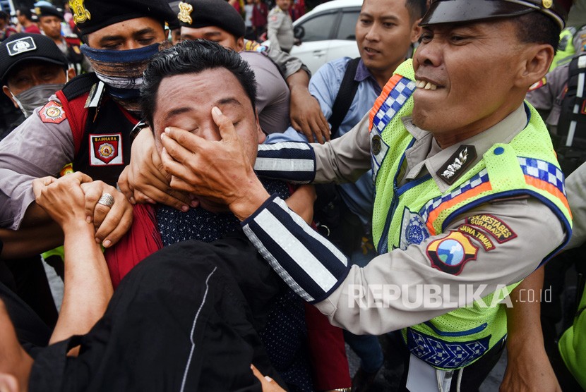 Seorang mahasiswa yang tergabung dalam Jaringan Mahasiswa Pejuang diamankan petugas saat aksi menggugat revisi UU MD3 di depan Gedung DPRD Surabaya, Jawa Timur, Senin (26/2). 