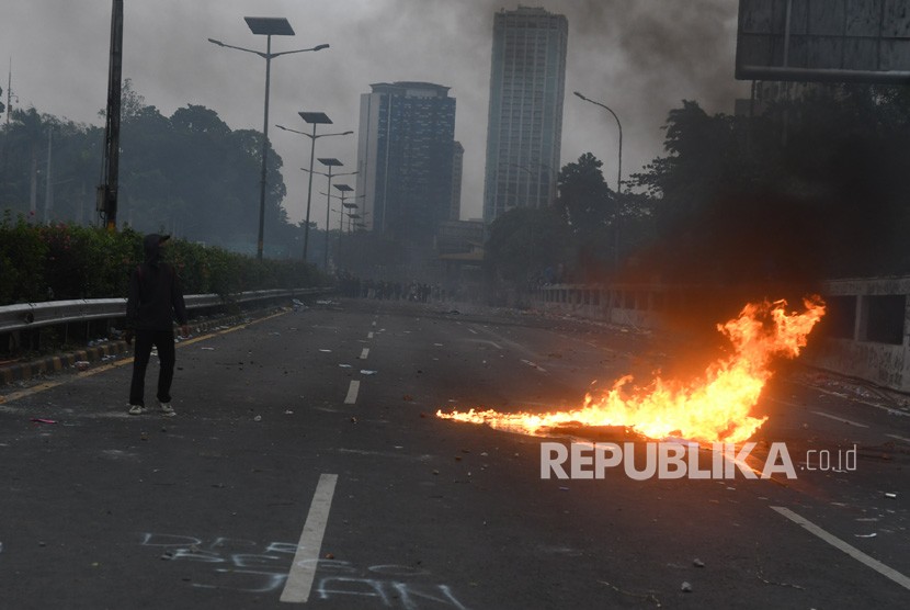 Seorang mahasiwa melintas di jalan Tol saat terjadi bentrokan dengan petugas kepolisian saat berunjuk rasa di depan gedung DPR RI, Jakarta, Selasa (24/09/2019).