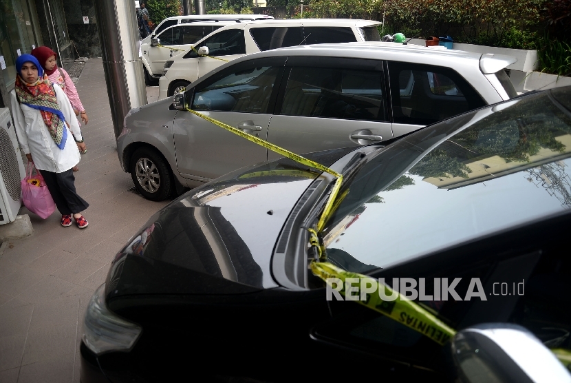 Seorang melintas disamping mobil sitaan milik bos First Travel di halaman Bareskrim Polri, Jakarta, Senin (14/8).