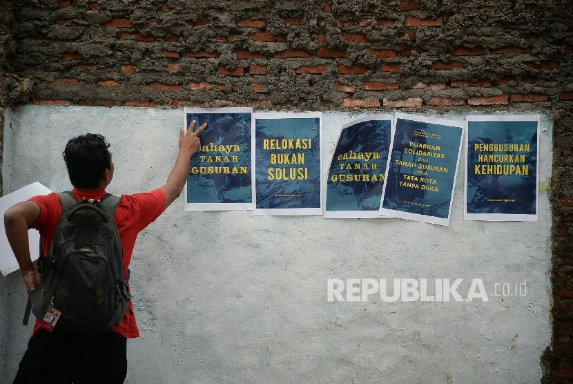  Seorang memempelkan poster acara kegiatan peduli sosial bertajuk Cahaya Tanah Gusuran di Lokasi Gusuran Bukit Duri, Jakarta, Sabtu (15/10).