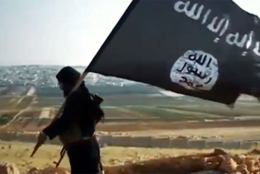 Seorang milisi membawa bendera kelompok teroris ISIS.