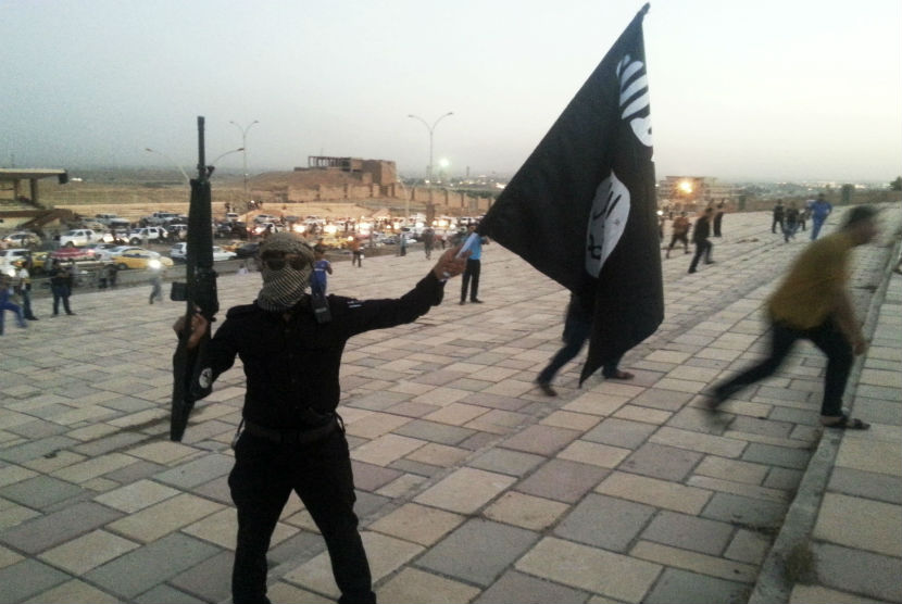 Seorang militan ISIS memegang senjata dan bendera ISIL di Mosul, Irak, pada 23 Juni lalu. (file foto)