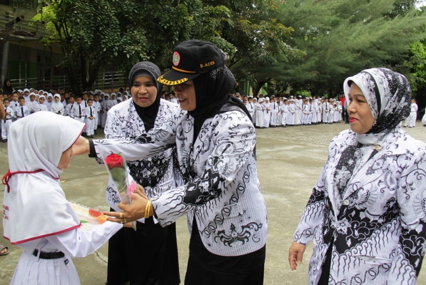 Seorang murid menghadiahkan bunga kepada gurunya saat upacara peringatan Hari Guru Nasional di SDN 1 Banda Aceh, Rabu (25/11).