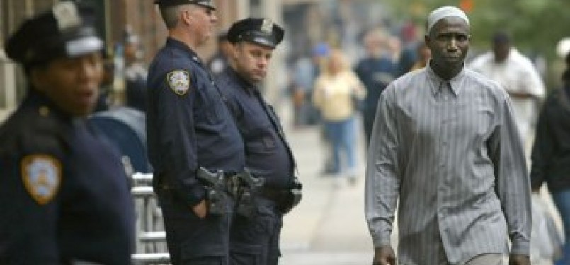 Seorang Muslim berjalan melintas di depan petugas polisi kota New York (NYPD) yang sedang bertugas.