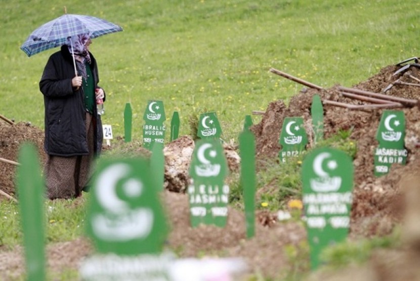 Seorang muslim Bosnia  berdiri menyaksikan makam korban perang Serbia.