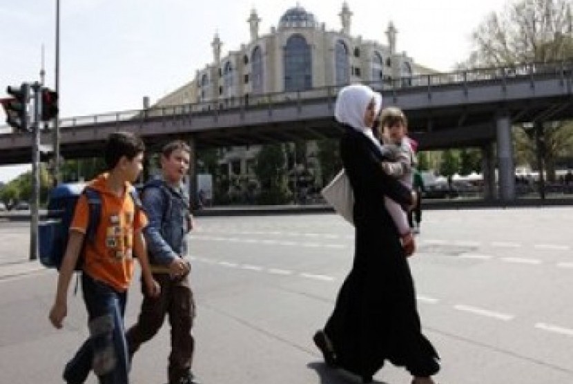 Seorang Muslimah melintas di jalan raya dengan latar belakang masjid Berlin. Pihak berwenang Berlin mengkonfirmasi pada Rabu (29/3/2023), negara bagian di Jerman ini akan mengizinkan guru Muslim mengenakan jilbab.