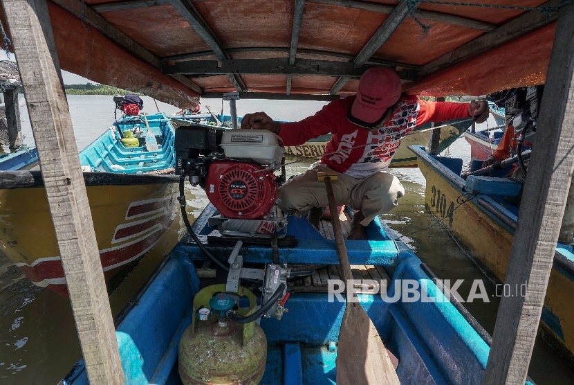 Seorang nelayan menyalakan mesin perahu yang telah dikonversi menggunakan bahan bakar elpiji.