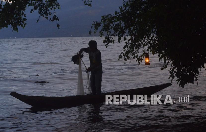 Seorang nelayan menyiapkan jala diterangi lentera, di Danau Singkarak, Nagari Sumpu, Kabupaten Tanah Datar, Sumatera Barat, Rabu (25/8/2021). Sebagian kecil nelayan di daerah itu masih menggunakan lentera berbahan minyak tanah sebagai alat penerangan untuk membantu menerangi aktivitas menjala.