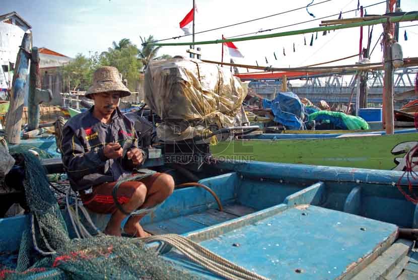 Seorang nelayan, Rosid (31) mengisi waktu luang dengan menjahit jaring di kapalnya yang berlabuh di Pantai Utara kawasan Eretan, Indramayu, Selasa (26/8)(Republika/Raisan Al Farisi)