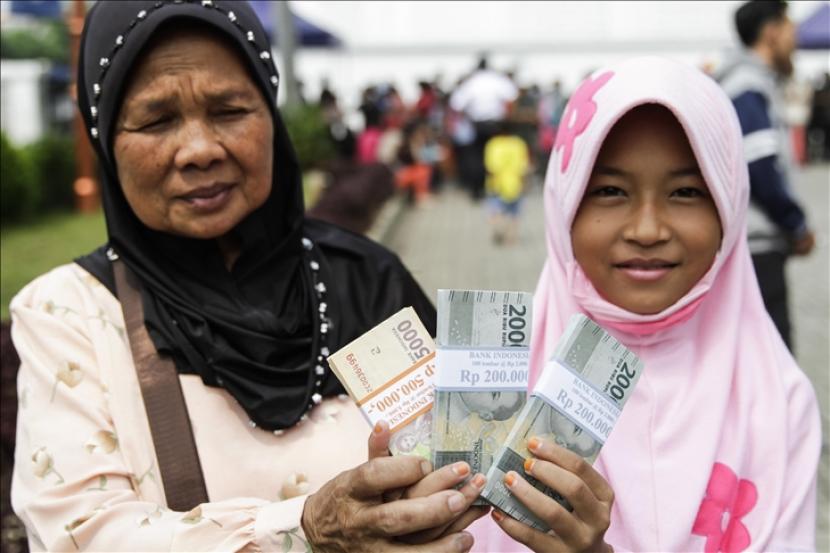 Seorang nenek bersama cucunya memperlihatkan uang pecahan kecil usai mengantre menukarkan uang di mobil kas keliling di Museum Bank Indonesia, Jakarta,