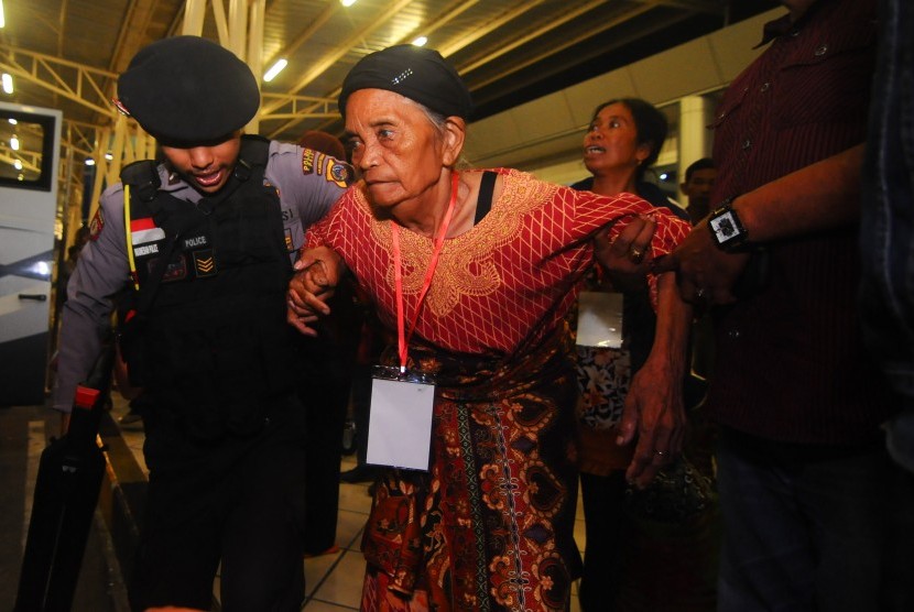Seorang nenek eks-Gerakan Fajar Nusantara (Gafatar) dibantu berjalan oleh Polisi saat tiba di Bandara Mutiara Sis Aljufri Palu, Sulawesi Tengah, Kamis (11/2) malam.