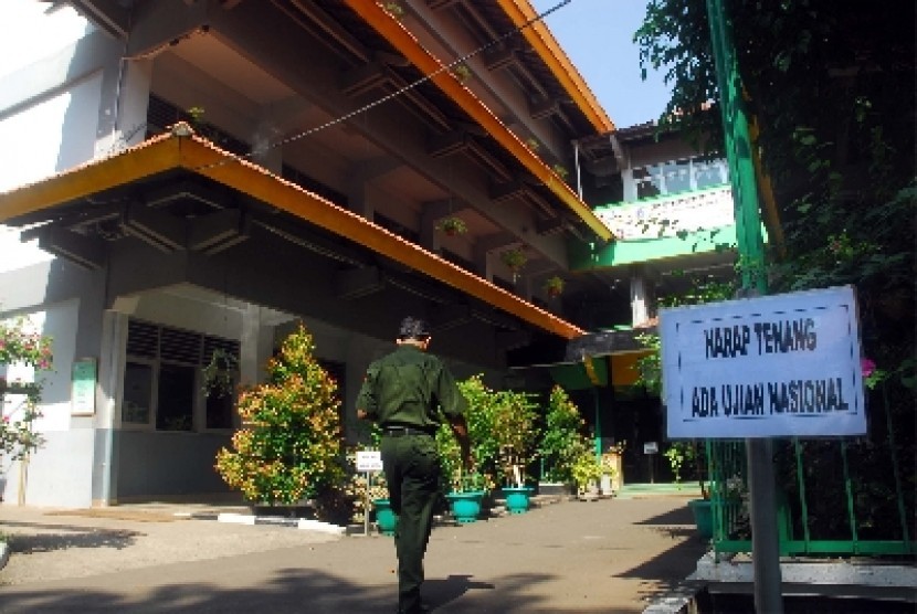 Seorang panitia Ujian Nasional (UN) melintas didepan Sekolah Menengah Kejuruan (SMK) Negeri 8 Jakarta saat UN berlangsung, Senin (16/4). 