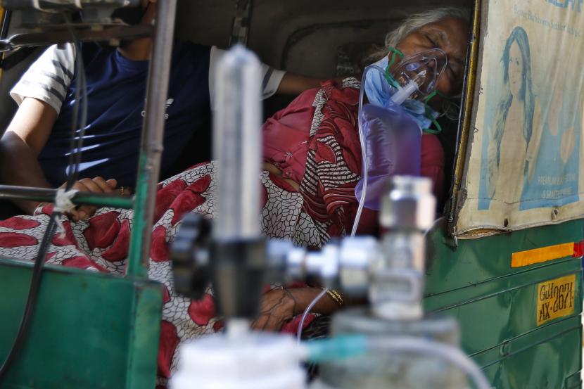 Seorang pasien COVID-19 bernapas dengan bantuan masker oksigen dan menunggu di dalam becak mobil untuk dirawat dan dirawat di rumah sakit pemerintah khusus COVID-19 di Ahmedabad, India, Sabtu, 17 April 2021. 