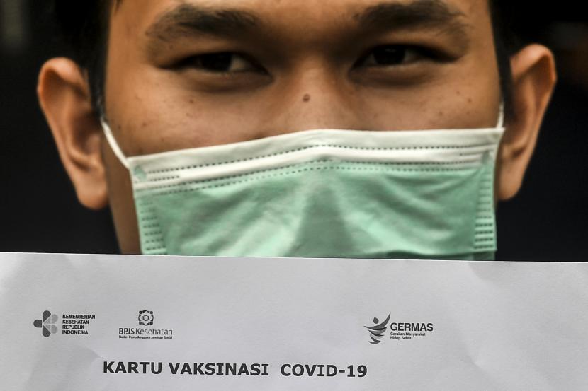 Seorang pasien menunjukkan kartu vaksinasi COVID-19 saat simulasi pemberian vaksin COVID-19 Sinovac di Puskesmas Kelurahan Cilincing I, Jakarta, Selasa (12/1/2021). Simulasi tersebut digelar sebagai persiapan penyuntikan vaksinasi COVID-19 yang rencananya akan dilakukan oleh pemerintah pada 13 Januari 2021.