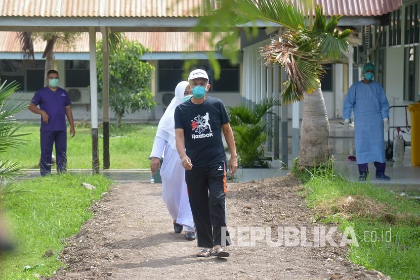 Seorang pasien positif Covid-19 (depan) yang dinyatakan sembuh berjalan menuju ruang tunggu saat proses pemulangan di Rumah Sakit Zainal Abidin, Banda Aceh.