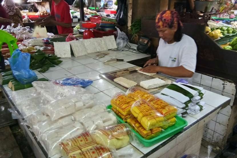 Seorang pedagang, Becky (30 tahun) di Pasar Tebet Barat, Kamis (6/9) tengah mengiris tempe untuk dibungkus dengan daun pisang. Harga tempe dan tahu belum mengalami kenaikan meski rupiah terus melemah dan memicu kenaikan harga kedelai impor. Pedagang memilih untuk mengecilkan ukuran agar keuntungan yang diperoleh tetap sama.  