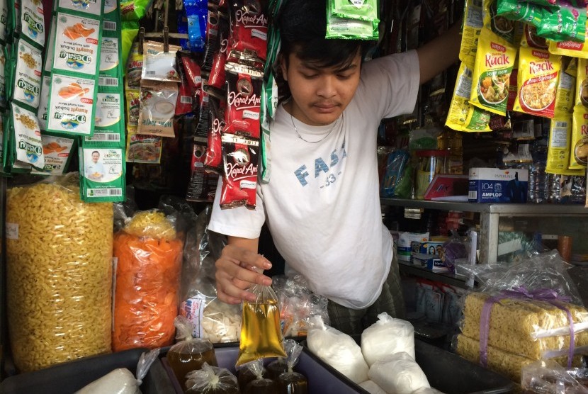 Seorang pedagang di Pasar Cikurubuk Kota Tasikmalaya menunjukkan minyak goreng curah yang masih dijual bebas di pasaran, Senin (7/10).