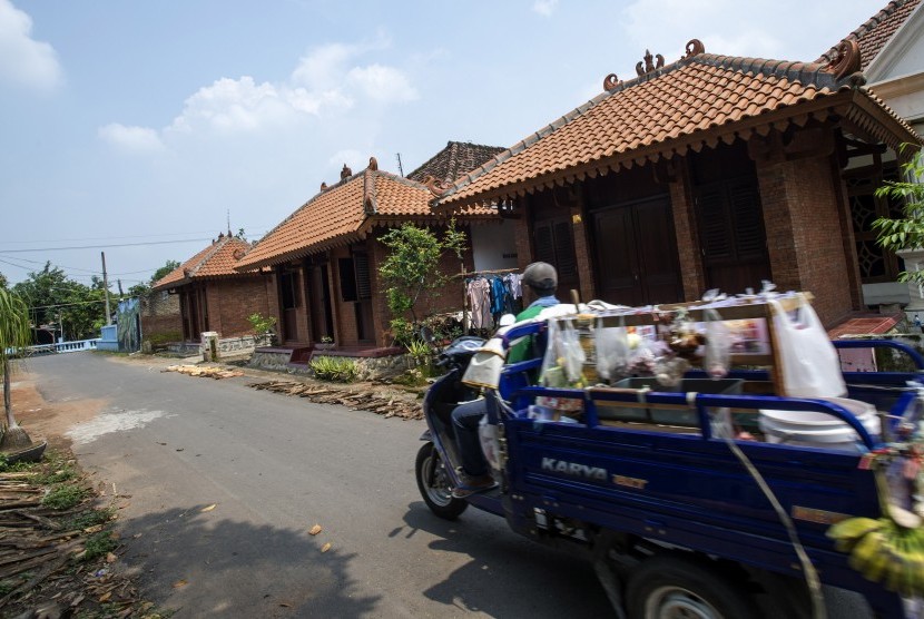 Seorang pedagang keliling melintas di depan deretan rumah bergaya arsitektur Majapahit di Desa Bejijong, Kawasan Cagar Budaya Nasional Trowulan, Mojokerto, Jawa Timur, Kamis (10/3).