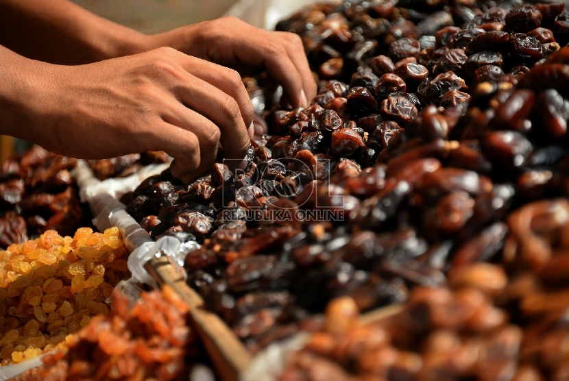 Seorang pedagang kurma menata barang dagangannya 