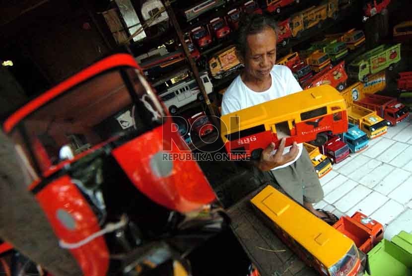 Seorang pedagang mainan mobil kayu, Umar (73) merapikan mainan yang ia jual di Jalan Raya Pasar Minggu, Jakarta Selatan (15/9). (Republika/Raisan Al Farisi).