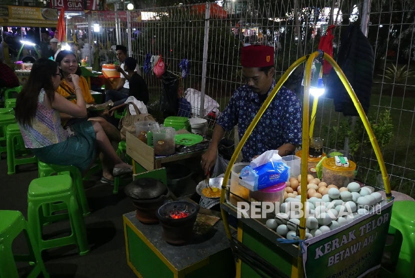 Seorang pedagang makanan khas Betawi, Kerak Telor, sedang menyiapakn pesanan pelanggannya di areal Pekan Raya Jakarta (PRJ) Selasa (13/6). 