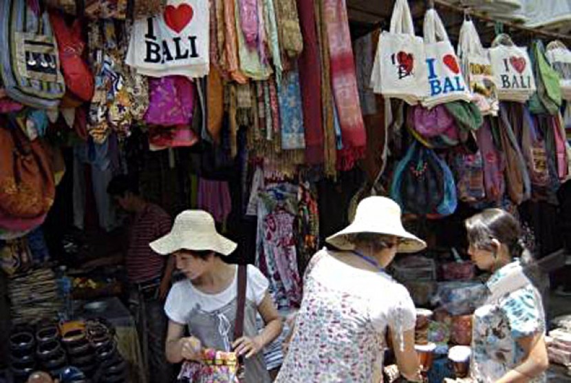 Seorang pedagang melayani wisatawan asing saat mereka berbelanja di Pasar Seni Ubud, Bali.