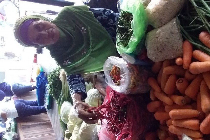 Seorang pedagang memegang dagangan cabai miliknya di sebuah pasar di Yogyakarta.