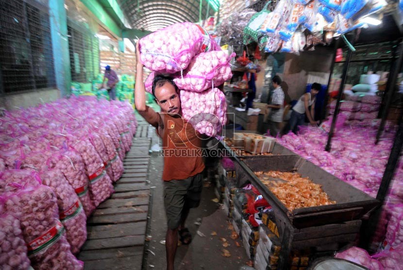 Seorang pedagang mengangkut bawang putih di Pasar Induk Kramat Jati, Selasa (26/3).  (Republika/Wihdan Hidayat)