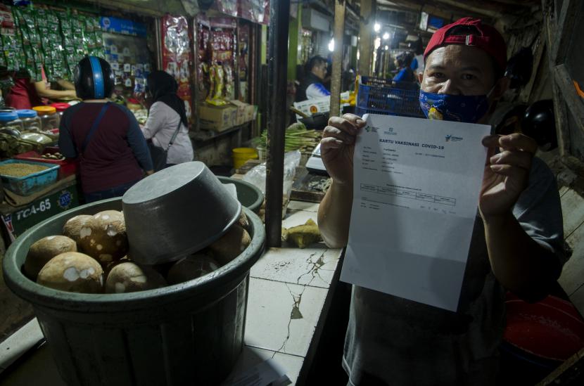 Seorang pedagang menunjukkan bukti vaksinasi COVID-19 usai disuntik di Pasar Sederhana, Bandung, Jawa Barat, Sabtu (27/2/2021). Sedikitnya 200 pedagang di pasar tersebut menerima vaksin COVID-19 dosis pertama pada pelaksanaan vaksin tahap dua Jawa Barat yang ditujukan bagi lansia, pedagang pasar, ASN,TNI-Polri.