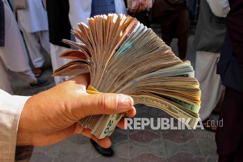  Seorang pedagang penukaran mata uang menghitung Afgani ketika orang-orang berkumpul untuk menarik uang dari sebuah bank di Kabul, Afghanistan, Ahad (12/9).