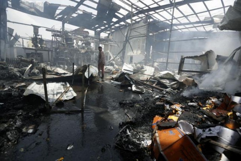 Seorang pegawai berjalan di dalam pabrik makanan ringan yang hancur dihantam serangan udara koalisi Arab Saudi di Sanaa, Yaman.