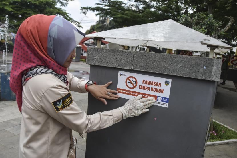 Seorang pegawai Dinas Kesehatan Kota Tasikmalaya menggelar aksi simpatik dengan menempelkan stiker peringatan saat aksi Hari tanpa Tembakau Sedunia di Taman Kota Tasikmalaya, Jawa Barat, Selasa (31/5/2022). 