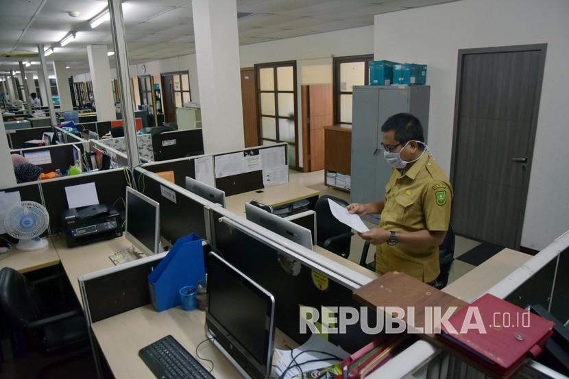 Seorang pegawai negeri sipil (PNS) Pemprov Riau mengenakan masker saat mendapat giliran masuk bekerja di Dinas Komunikasi Informatika dan Statistik Riau, di Kota Pekanbaru, Senin (20/4).  