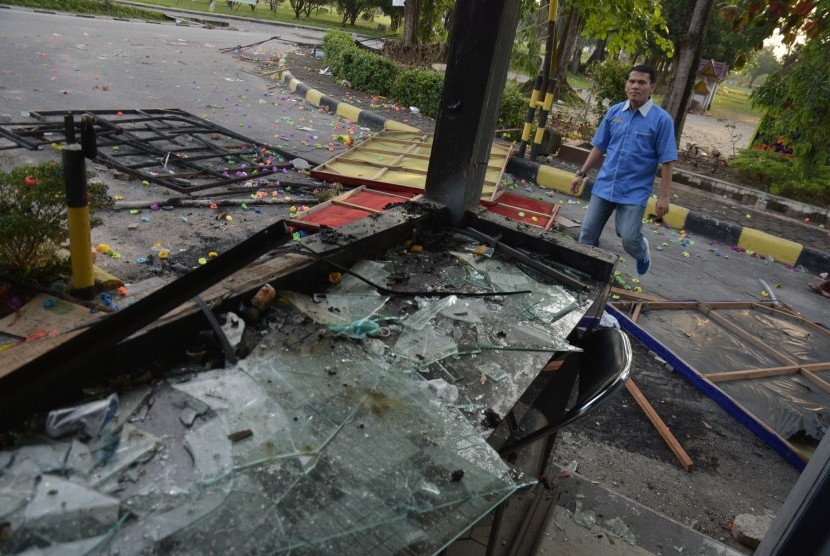Seorang pegawai Rektorat Universitas Riau melintasi pos keamanan yang rusak parah akibat bentrokan di Gedung Fakultas Ilmu Sosial dan Politik Universitas Riau, di Kota Pekanbaru, Jumat (6/10). 