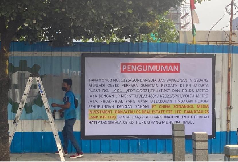 Seorang pejalan kaki melintasi baliho peringatan sengketa di depan pintu masuk proyek pembangunan gedung Indonesia 1, di Jalan MH Thamrin, Jakarta.