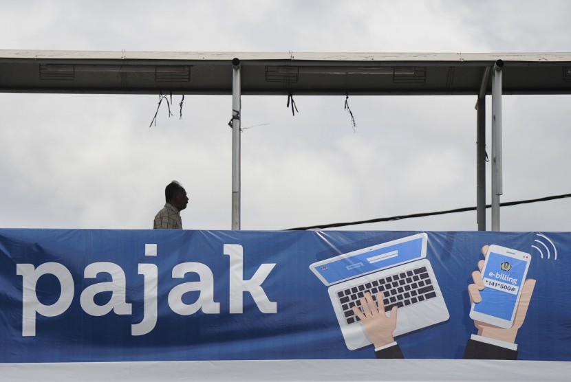 Seorang pejalan kaki melintasi papan sosialisasi pembayaran pajak secara online di Jakarta, Selasa (1/3).