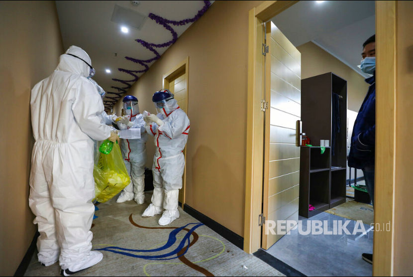 Seorang pekerja dengan pakaian pelindung disemprot cairan desinfektan saat keluar dari hotel yang digunakan sebagai tempat isolasi warga di Wuhan, Hubei, China, senin(3/2). 