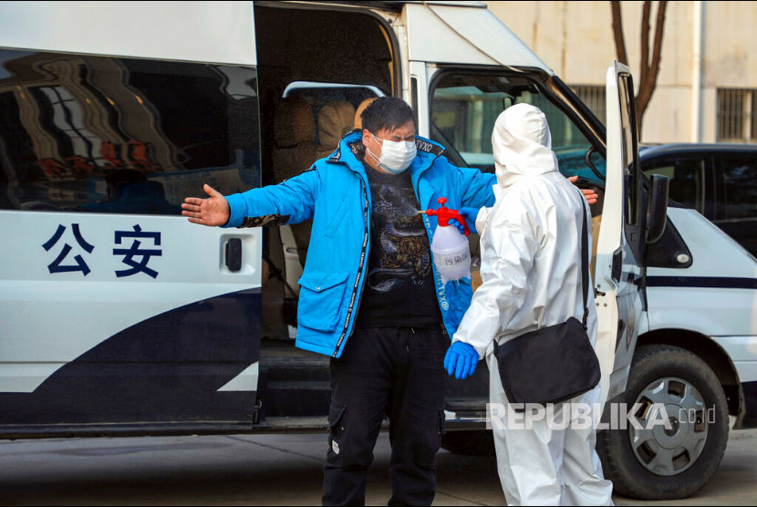 Seorang pekerja dengan pakaian pelindung disemprot cairan desinfektan saat keluar dari hotel yang digunakan sebagai tempat isolasi warga di Wuhan, Hubei, China, senin(3/2). 