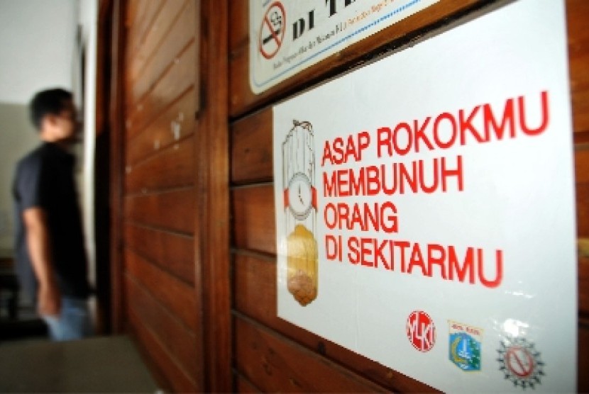 Seorang pekerja melintas disamping poster larangan merokok di dalam ruangan di salah satu kantor dikawasan Duren Tiga, Jakarta Selatan.