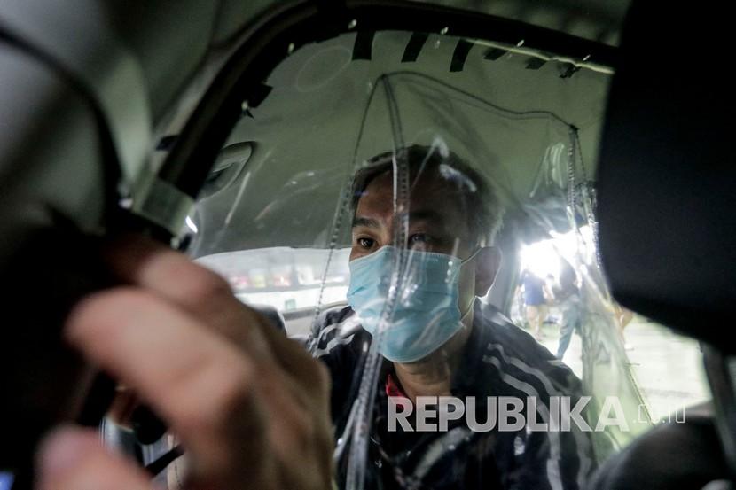 Seorang pekerja memakai masker memasang penutup pelindung untuk mencegah penyebaran virus corona di dalam taksi di bengkel ComfortDelgro, Singapura. Singapura mulai pelonggaran pembatasan sosial fase kedua hari ini. Ilustrasi.