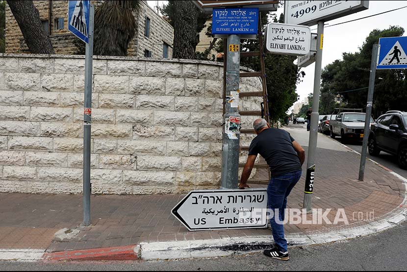 Seorang pekerja memasang rambu penunjuk arah menuju Kedutaan Besar AS di Kawasan Jerusalem Palestina, Senin (7/5)