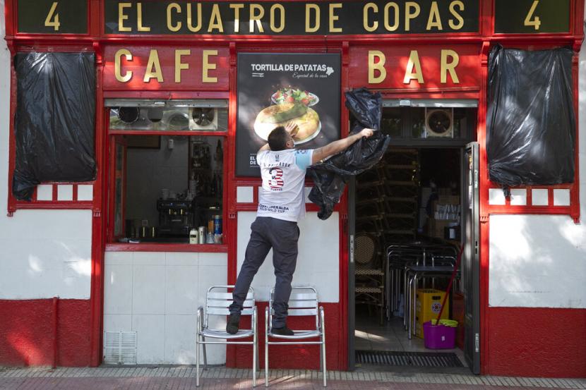  Seorang pekerja membuka selubung cafe di Madrid, Spanyol, Senin (25/5) yang siap dibuka kembali setelah tutup selama dua bulan.