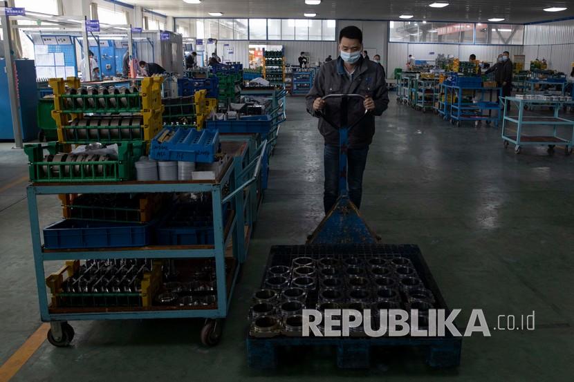 Seorang pekerja memindahkan suku cadang untuk membuat gearbox di pabrik. Lebih dari selusin perusahaan di Zhejiang China stop produksi sementara. Ilustrasi.